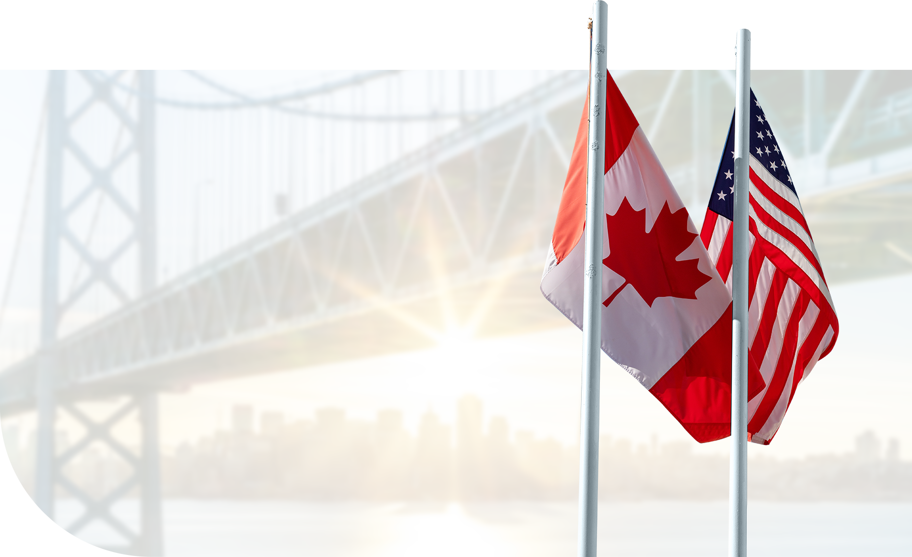 A Canadian and an America flag, with a cross border bridge in the background.